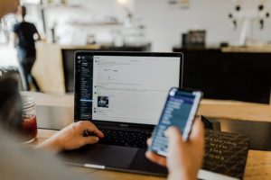 person on laptop using project management tool and holding a mobile device