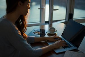 Woman sitting at desk with working on open laptop