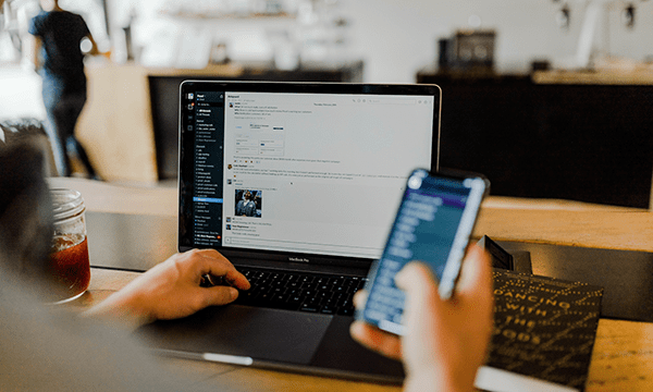 person on laptop using project management tool and holding a mobile device