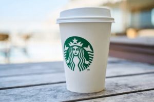 Closer upshot of Starbucks cup on outdoor patio, zoomed into beauty shot of the logo a proprietary cup design